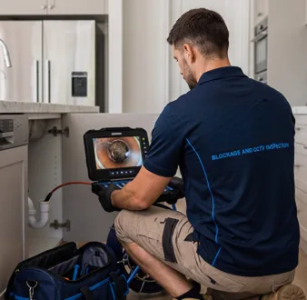 Plumber clearing a blocked toilet in a Newington bathroom